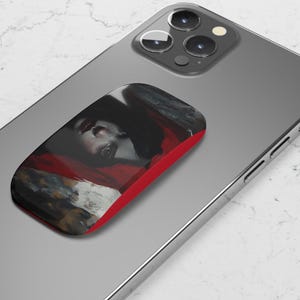 May include: A red phone grip with a black and white image of a woman's face. The grip is attached to a silver smartphone.