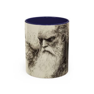May include: A white ceramic mug with a dark blue interior. The exterior features a detailed black and white illustration of an elderly man with a long white beard and the text "...often..." in a script font.