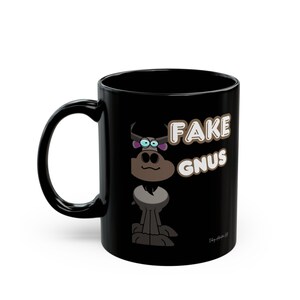 Puede incluir: Taza de cerámica negra con una ilustración de dibujos animados de un ñu y el texto "FAKE GNUS". El ñu tiene ojos azules y un cuerpo gris. La taza tiene un asa curva.