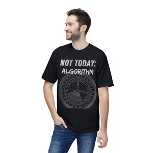 May include: Black t-shirt with the text "NOT TODAY: ALGORITHM" in white. Below the text is a circular design with letters and a central pointer. The person is wearing blue jeans.