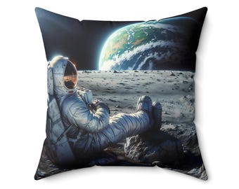 May include: Square throw pillow featuring an astronaut relaxing on the moon, with Earth visible in the background. The astronaut is wearing a silver spacesuit. The pillow has a black border.