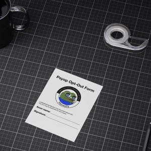 May include: A white "Psyop Opt-Out Form" with a cartoon frog graphic and the word "Honestly". The form includes fields for an anon name and signature. A roll of tape, a black mug, and a pencil are also on the black grid surface.