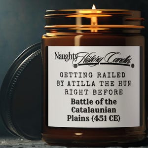 Pode incluir: Um frasco de vela de vidro castanho com um rótulo branco que diz "Naughty History Candles" e "GETTING RAILED BY ATILLA THE HUN RIGHT BEFORE Battle of the Catalaunian Plains (451 CE)".