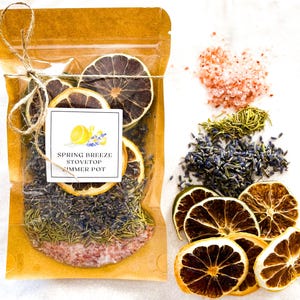 May include: A brown paper bag with a clear plastic window filled with dried citrus fruit, lavender, rosemary, and pink Himalayan salt. The bag is tied with twine and has a label that reads "Spring Breeze Stovetop Simmer Pot".