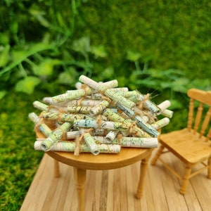 1:12 scale Miniature map scrolls tied with jute string are displayed on a miniature wooden table. The maps are mainly coloured white, green and blue