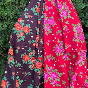 May include: A fabric textile featuring two distinct sections of floral patterns. The left side is a dark brown background with orange and red roses and green leaves. The right side is a bright red background with pink roses and green leaves.