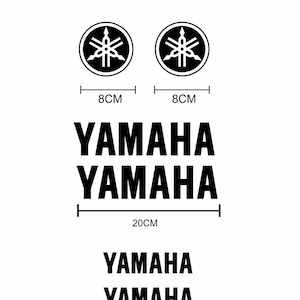 Può includere: Adesivi con logo Yamaha bianchi. L'immagine mostra due loghi circolari, ciascuno di 8 cm di diametro, e due serie della parola "YAMAHA" in grassetto, una serie larga 20 cm e l'altra 12 cm. Il logo del negozio "amaf shop" si trova nell'angolo in alto.