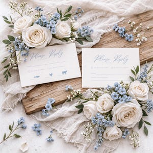May include: Two invitation cards with the words "Please Reply" in elegant script, surrounded by white roses and blue flowers. The cards are on a wooden board with a white fabric backdrop. The cards have icons of a fish, chicken, and cow.