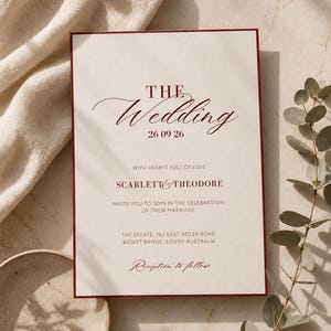 May include: A rectangular wedding invitation card with a dark red border on a cream background. The text reads: THE Wedding 26 09 26 WITH HEARTS FULL OF LOVE SCARLETT & THEODORE INVITE YOU TO JOIN IN THE CELEBRATION OF THEIR MARRIAGE THE ESTATE, 762 EAST ADLER ROAD BASKET RANGE, SOUTH AUSTRALIA Reception to follow.
