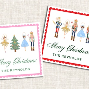 May include: Two holiday-themed gift tags with a white background and scalloped borders. One tag has a pink border, the other a red border. Each features illustrations of Nutcracker characters and the text "Merry Christmas" and a name.