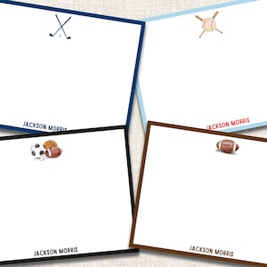 May include: Four white notecards with sports-themed illustrations and colored borders. The top left card has a navy blue border and golf clubs. The top right card has a light blue border and a baseball. The bottom left card has a black border with a soccer ball, basketball, and football. The bottom right card has a brown border and a football. Each card has the name "JACKSON MORRIS" printed at the bottom.