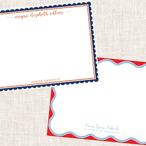 May include: Two rectangular stationery cards. The top card has a navy blue scalloped border, an orange inner frame, and the text "Megan Elizabeth Collins" and "Auburn University". The bottom card has a red scalloped border, a light blue inner frame, and the text "Emma Grace Roberts" and "University of Mississippi".