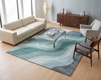 May include: A rectangular area rug featuring a layered, wavy pattern in various shades of teal, light blue, and gray. The rug has a soft, textured appearance with distinct curved lines that create a flowing, topographical design across the surface.
