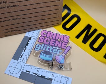 Può includere: Un distintivo trasparente con le parole "CRIME SCENE glitter" in rosa e blu, con un pennello per il trucco e un contenitore di polvere. Sono visibili anche un sacchetto di prove marrone, un nastro giallo "DO NOT CROSS" e un righello forense.
