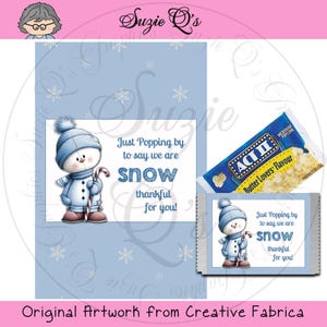 Puede incluir: Tarjeta azul claro con una ilustración de muñeco de nieve sosteniendo un bastón de caramelo, con el texto "Just Popping by to say we are snow thankful for you!". Incluye una bolsa de palomitas.
