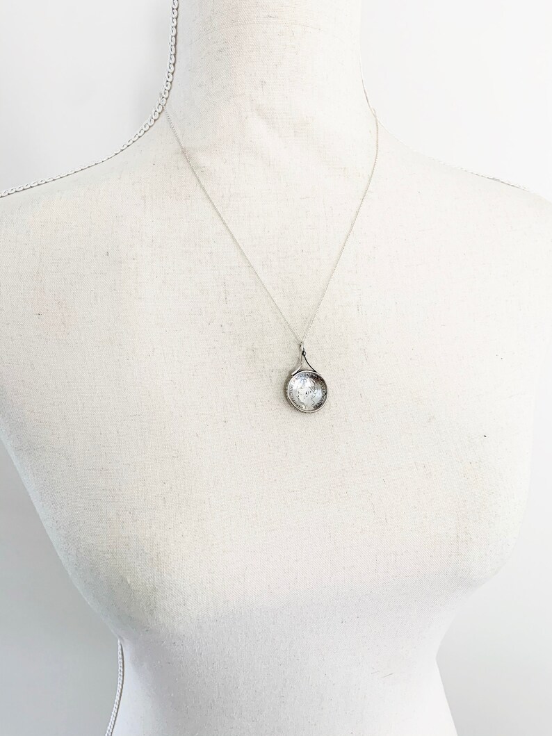May include: A silver chain necklace with a round pendant featuring a clear glass design.