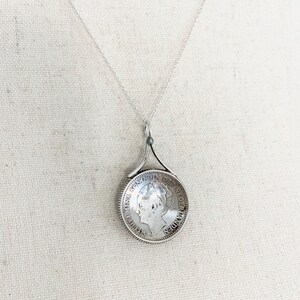 May include: Silver necklace with a pendant featuring a vintage Dutch coin with the inscription "KONINGIN DER NEDERLANDEN" and a profile of Queen Wilhelmina.