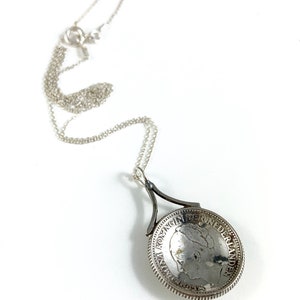 May include: Silver necklace with a pendant featuring a vintage Dutch coin with the inscription "KONINGIN DER NEDERLANDEN".