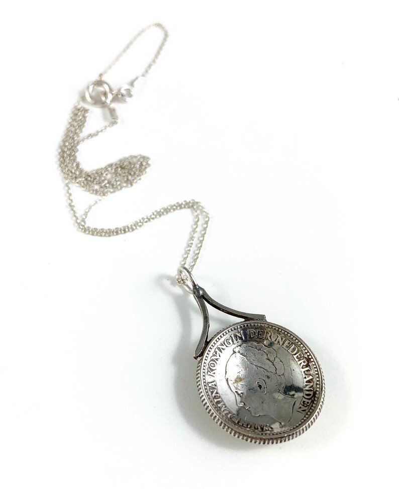 May include: Silver necklace with a pendant featuring a vintage Dutch coin with the inscription "KONINGIN DER NEDERLANDEN".