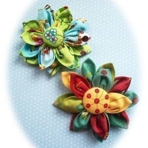 May include: Two fabric flowers with multiple layers of colourful fabric. The flowers have a button centre and are made with a variety of patterns.
