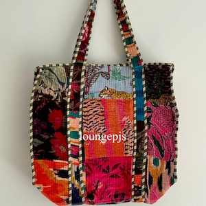 Könnte beinhalten: Eine Patchwork-Tragetasche mit einem lebendigen Design. Die Tasche weist eine Vielzahl farbenfroher Stoffe auf, darunter Blumen- und Tiermuster. Die Griffe und Kanten sind mit einem kontrastierenden grün-weiß gestreiften Stoff versehen. Der Text "loungepjs" ist sichtbar.