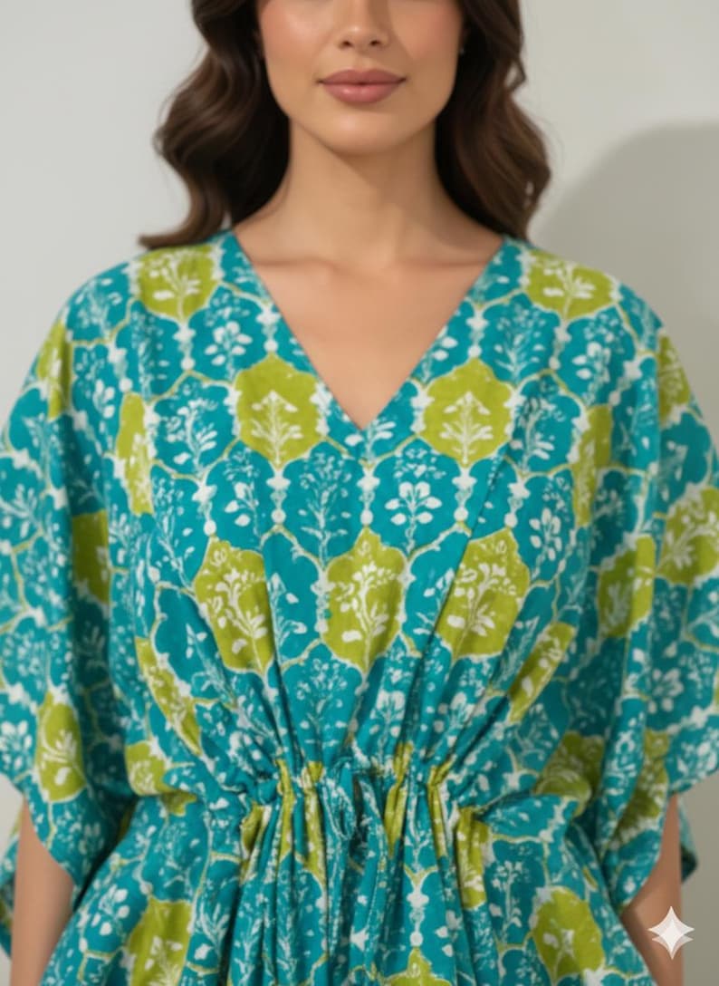 K&ouml;nnte beinhalten: T&uuml;rkis- und limettengr&uuml;nes Kaftankleid mit V-Ausschnitt und Kordelzug in der Taille. Der Stoff hat ein sich wiederholendes Blumenmuster in Wei&szlig;, Limettengr&uuml;n und T&uuml;rkis. Das Kleid hat kurze &Auml;rmel und eine lockere Passform.