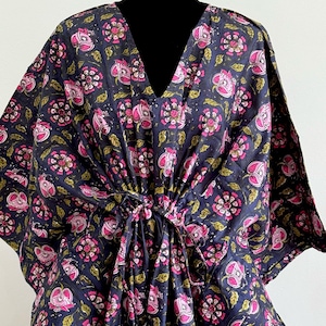 K&ouml;nnte beinhalten: Ein dunkelblauer Kaftan mit V-Ausschnitt und einem Blumenmuster in Rosa und Gr&uuml;n. Der Kaftan hat einen Kordelzug in der Taille und ist aus leichtem Stoff gefertigt.