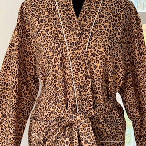 May include: A brown and tan leopard print robe with a white trim and a matching tie belt.