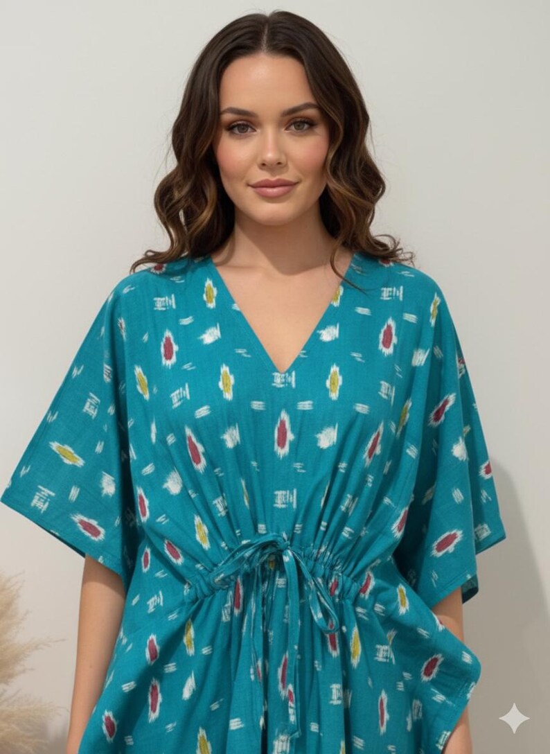 K&ouml;nnte beinhalten: Ein t&uuml;rkisfarbenes Kaftan-Kleid mit V-Ausschnitt und Bindeg&uuml;rtel. Das Kleid hat ein sich wiederholendes Muster aus wei&szlig;en, roten und gelben Formen. Die &Auml;rmel sind weit und der Stoff scheint leicht zu sein. Das Kleid ist ein bequemer, l&auml;ssiger Stil.