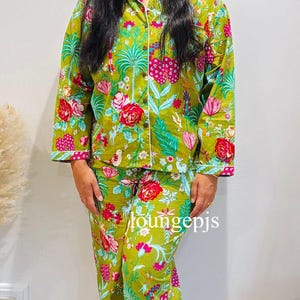 May include: A green and white floral print pyjama set with long sleeves and trousers. The top has a button-up front and a white trim. The trousers have a drawstring waist. The text "loungepjs" is visible on the trousers.