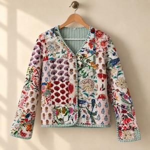 May include: A quilted jacket featuring a patchwork design with various floral and botanical patterns in shades of red, blue, green, and yellow. The jacket has a V-neckline, long sleeves, and a front button closure with light-colored buttons.