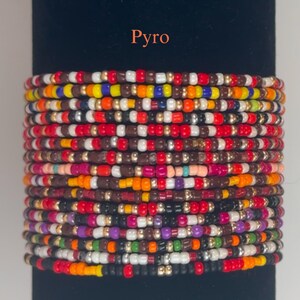 以下が含まれることがあります： 赤、オレンジ、黄色、緑、青、紫、茶色、黒、白など、さまざまな色を使用したマルチカラービーズブレスレット。ブレスレットは、ランダムなパターンで糸に通された小さな丸いビーズで作られています。ブレスレットの名前は「Pyro」です。