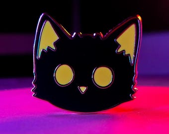 May include: A black cat-shaped enamel pin with yellow accents on the ears and eyes. The pin has a shiny, metallic border and a small, triangular nose. The background is a gradient of pink and purple.