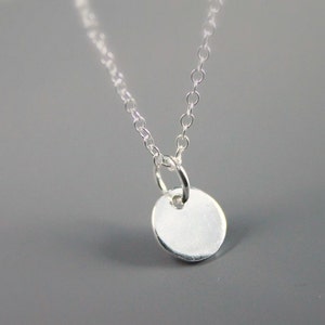 May include: A silver chain necklace with a small, round, silver pendant.
