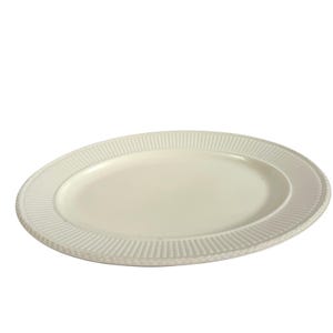 May include: An oval-shaped white ceramic serving platter featuring a smooth, recessed center and a wide, raised rim decorated with a repeating vertical ribbed pattern and a delicate braided texture along the outer edge of the plate.