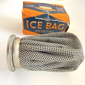 May include: Vintage ice bag with a black and white checkered pattern, a metal cap, and an orange and blue box. The box reads "ICE BAG" and "QUALITY DAVOL".