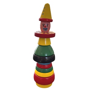 Puede incluir: Un juguete apilable de madera de colores con forma de payaso. El payaso tiene un sombrero amarillo, un cuello rojo y una cara pintada. El juguete está hecho de varias piezas de madera pintadas de diferentes tamaños en rojo, amarillo, verde, negro y azul.