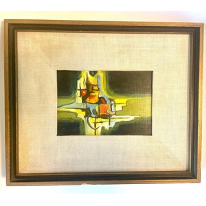 May include: Abstract painting in a wooden frame. The artwork features a central composition with yellow, orange, and green hues. The painting is framed with a gold-colored inner border and a dark outer border, set against a neutral linen background.