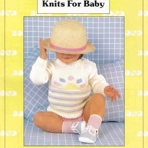 May include: A Simplicity Knits For Baby pattern booklet featuring a straw hat with a pink ribbon, a white long-sleeved sweater with pastel stripes and a sun motif, pink socks, and blue and white striped T-strap shoes on a light blue grid background.