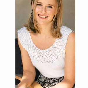 May include: A white sleeveless top featuring a delicate diamond-patterned knit yoke and a ribbed bodice. The garment is paired with dark-toned, patterned shorts, dark chain-link drop earrings, and a thick, mottled brown and black resin bangle.