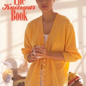 May include: A bright yellow long-sleeved knit cardigan with a V-neckline and a vertical row of small buttons down the front. The text "The Knitwear Book" appears in red at the top left, and "KNITMASTER" with "Aneto 2ply Bouclé" at the bottom.