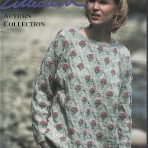 May include: A woman wearing a light gray sweater with a floral pattern. The sweater has a crew neck and long sleeves. The image is from the "Gold Collection" Autumn Collection, issue number 29, with patterns for bond knitters.