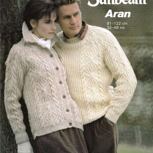 Puede incluir: Jerséis y cárdigan de punto Aran color crema. El cárdigan tiene cierre de botones y bolsillos. Los jerséis tienen diseños de trenzas y rombos. La imagen incluye el texto "1026 Sunbeam Aran" y medidas de 81-122 cm.