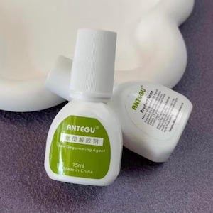 May include: Two white bottles of ANTEGU New Degumming Agent. One bottle is upright, the other is on its side. The upright bottle has a green label with Chinese characters and the text "15ml Made in China".