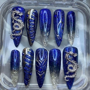 Puede incluir: Conjunto de diez uñas postizas de gelée azul y plata con diseños de dragón y espiral.