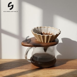 May include: A white ceramic mug with a black handle and the text "But First, Coffee" in a bold, black font. The mug is set against a blurred background, suggesting a cozy setting.