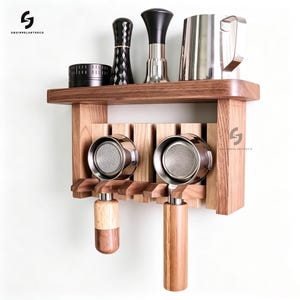 May include: A wall-mounted wooden espresso station featuring a shelf holding a black tamper, a metal tamper, and a stainless steel pitcher. Below, two portafilters with wooden handles are suspended from the rack. The SQUIRRELARTDECO logo is visible.