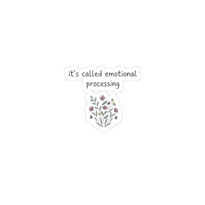 May include: A white sticker with the text "it's called emotional processing" in a black, sans-serif font. Below the text is a floral illustration with pink, yellow, and green elements.