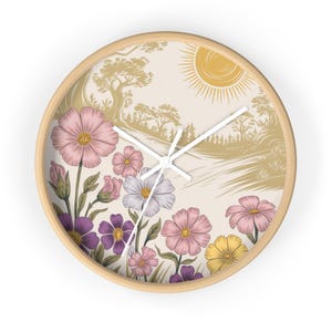 Könnte beinhalten: Eine runde Wanduhr aus Holz mit weißem Zifferblatt und schwarzen Zeigern. Das Zifferblatt der Uhr zeigt eine fantasievolle Illustration einer Sonne, Bäume und einen Weg, der mit rosa, lila und gelben Blumen gesäumt ist.