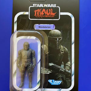 May include: A Star Wars Mandalorian action figure in a clear plastic case. The packaging is black with the Star Wars logo and the text "Maul Shadow Lord". The figure is gray and has a helmet and armor. The text "Mandalorian" is on the packaging.